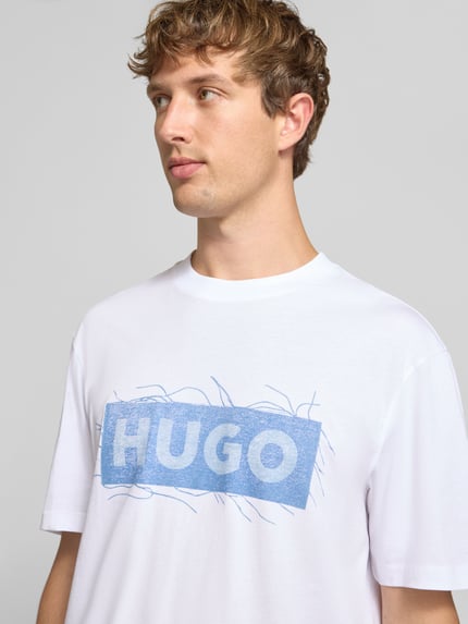 Męski model nosi Regular Fit T-Shirt aus reiner Baumwolle Modell 'Naxter' von HUGO z nadrukiem, biel, niebieski, tkanina gładka, Nahaufnahme Oberkörper, Męski t-shirt od HUGO Blue.