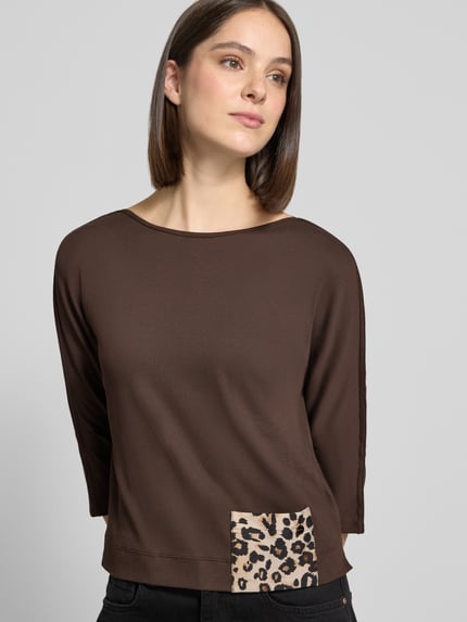 Frauenmodel trägt 3/4-Shirt mit seitlichem Patch-Detail von MARC CAIN in Braun, Animal Print Patch, Jersey, U-Boot-Ausschnitt, Nahaufnahme Oberkörper.