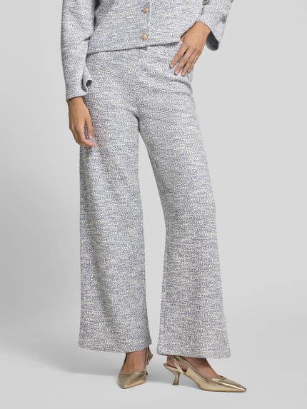 Frauenmodel trägt Hose in Bouclé-Optik mit elastischem Bund von Christian Berg Woman aus Baumwoll-Mix, Wide-Fit, hellgrau meliert, Nahaufnahme Unterkörper, ganz leicht strukturiertes Material erkennbar. Ganzkörperansicht von vorne.
