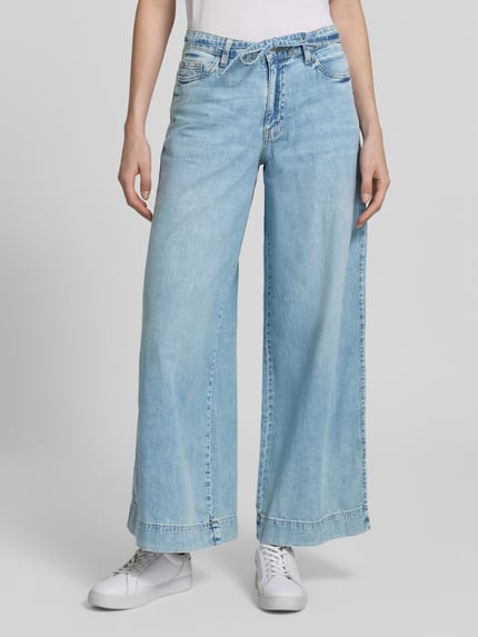 Kobieta modelka nosi Regular Fit Wide Leg Jeans aus reiner Baumwolle Modell 'AISA' od Vero Moda, stylizowana na denim, splot twill, krój regular fit, szlufki na pasek, zapięcie na guzik i zamek błyskawiczny, 5 kieszeni, bawełna, jasnoniebieski, widok całej sylwetki z przodu.