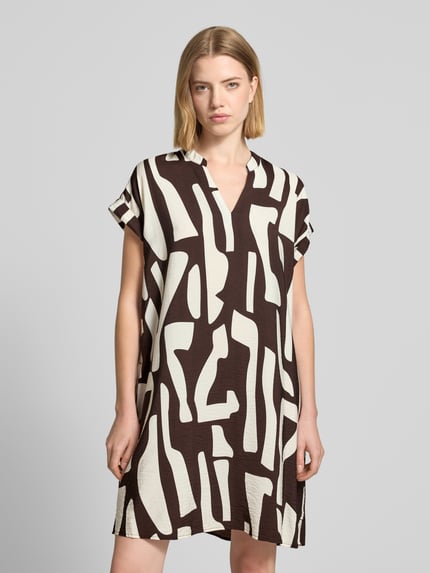 Vrouwenmodel draagt knielengte dames jurk van OPUS, viscosemix, loose fit, model 'Wulana dune', tuniekkraag, mouwen met vaste omslag. Vooraanzicht bovenlichaam.