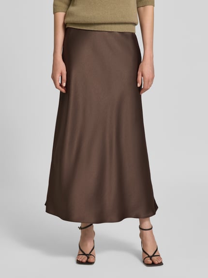Frauenmodel trägt Maxirock aus Satin mit elastischem Bund von Luisa Cerano in Braun, glatte Textur, A-Linie, Nahaufnahme Unterkörper.
