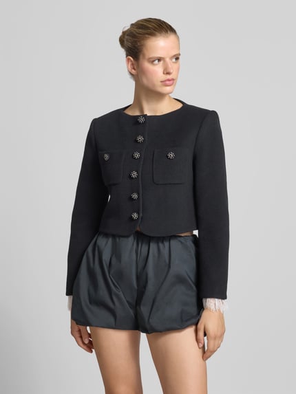 Frauenmodel trägt Jacke aus Woll-Mix mit Kaschmir-Anteil von Self-Portrait in Schwarz, Ziersteinbesatz, Brusttaschen, tailliert, Ganzkörperansicht von vorne.