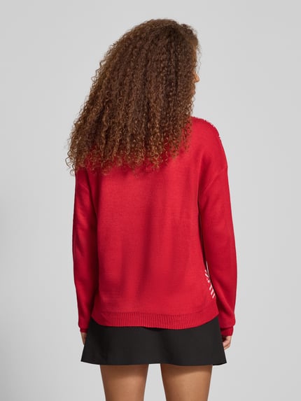 Frauenmodel trägt Regular Fit Strickpullover mit Weihnachtsmotiv Modell 'TEDDY' von Only in Rot, grafisches Muster, gerippte Abschlüsse, Ganzkörperansicht Rückansicht.