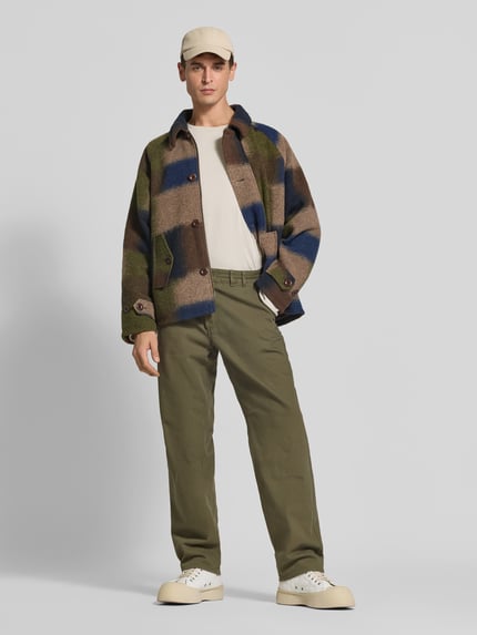 Männermodel trägt Jacke mit Woll-Anteil von Forét im Material-Mix, Regular Fit, gemusterte Farben, Ganzkörperansicht von vorne.