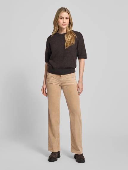 Frauenmodel trägt Bootcut Cordhose mit Eingrifftaschen Modell 'TESS' von Cambio in Beige, Baumwoll-Mix mit Modal, Ganzkörperansicht von vorne.
