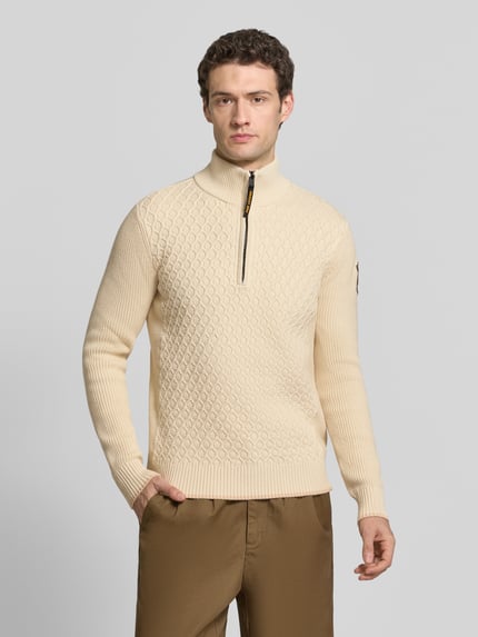 Męski model nosi sweter z dzianiny 'Strickpullover mit Stehkragen und Reißverschluss' od PME Legend, mieszanka bawełny, krój slim fit, fakturowany wzór, stójka, zamek błyskawiczny, długość tyłu w rozmiarze M 65 cm, długość rękawa w rozmiarze M 70 cm, kolor kremowy, faktura dzianiny, widok całej sylwetki z przodu.