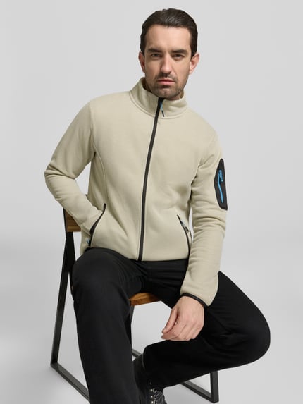 Männermodel trägt Regular fit Fleecejacke mit opstaande kraag Model 'BREDSTEDT' van Icepeak in licht beige met zwarte ritssluiting en steekzakken, context heren fleecejack, schouderbreedte 43 cm, borstwijdte 54 cm, mouwlengte 67 cm, ruglengte 69 cm, nahaufnahme oberkörper.