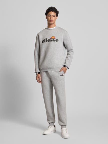 Mężczyzna nosi Sweatshirt mit Label-Print Modell 'CORVARO' od Ellesse, szary materiał-mix z wiskozą, luźny krój, ściągacze, przód, widok całej sylwetki