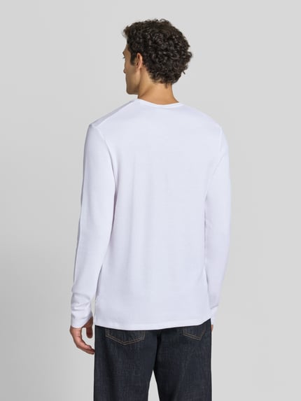 Männermodel trägt Regular Fit Longsleeve aus reiner Baumwolle Modell 'Basic' von Lindbergh, weiß, strukturierte Oberfläche, Ganzkörperansicht Rückansicht. Rückenlänge bei Größe M 73 cm, mit Rundhalsausschnitt.