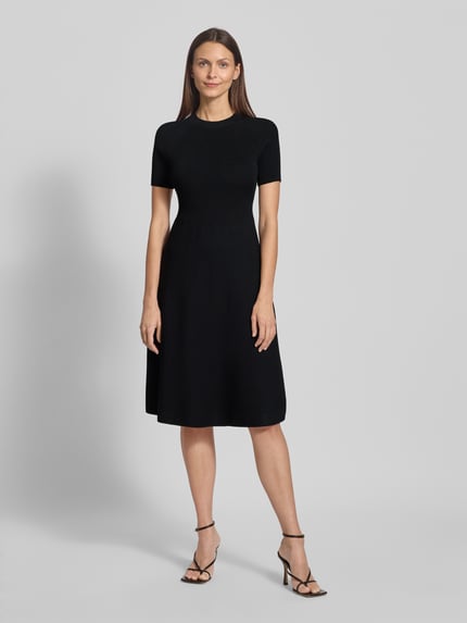Modelka kobieca nosi czarne, prążkowane knielang Strickkleid in Ripp-Optik mit 1/2-Arm von ARMANI EXCHANGE, dopasowany fason, widok z przodu całej sylwetki.