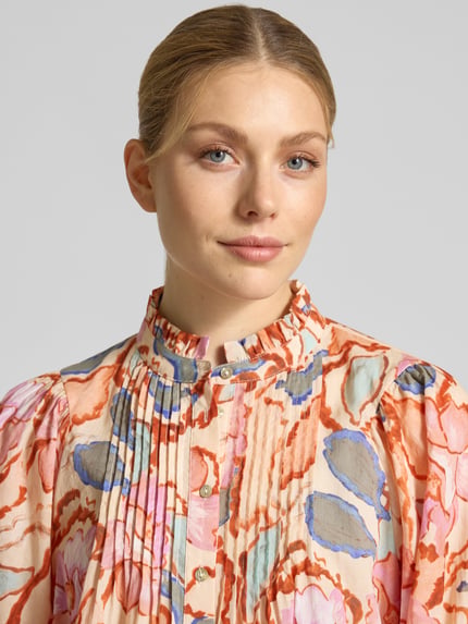 Frauenmodel trägt Regular Fit Bluse mit Stehkragen Modell 'LEYA' von SUNCOO PARIS aus reiner Baumwolle, bunter Allover-Look, Nahaufnahme Oberkörper.