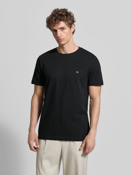 Męskimodel nosi T-Shirt aus Baumwolle mit Rundhalsausschnitt von Christian Berg Men, czarny, krój regular fit, detal z logo, okrągły dekolt, długość tyłu w rozmiarze M: 71 cm, Ganzkörperansicht von vorne.