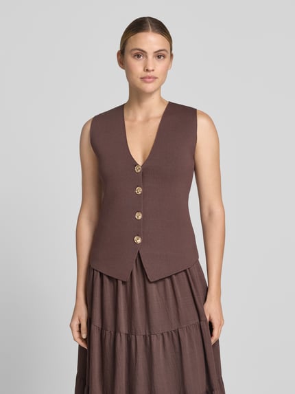 Frauenmodel trägt Strickweste mit V-Ausschnitt und Knopfleiste von Jake*s Cocktail aus Material-Mix mit Viskose-Anteil, Slim-Fit, braun, Rückenlänge bei Größe 36: 51 cm, Ganzkörperansicht von vorne.