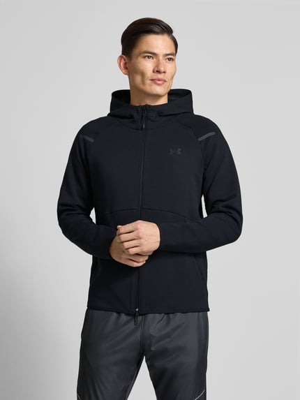 Männermodel trägt schwarze Trainingsjacke mit Zweiwege-Reißverschluss Modell 'Unstoppable' von Under Armour, Material-Mix mit Baumwoll-Anteil, Regular-Fit, Kapuze, Ganzkörperansicht von vorne.