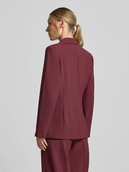 Frauenmodel trägt Regular Fit Blazer mit Reverskragen Modell 'Leonora' von MOS MOSH in Dunkelrot, glatte Textur, Ganzkörperansicht Rückansicht. Rückenlänge bei Größe 36: 68 cm, Brustweite 44 cm, Ärmellänge 63 cm, Knopfverschluss.