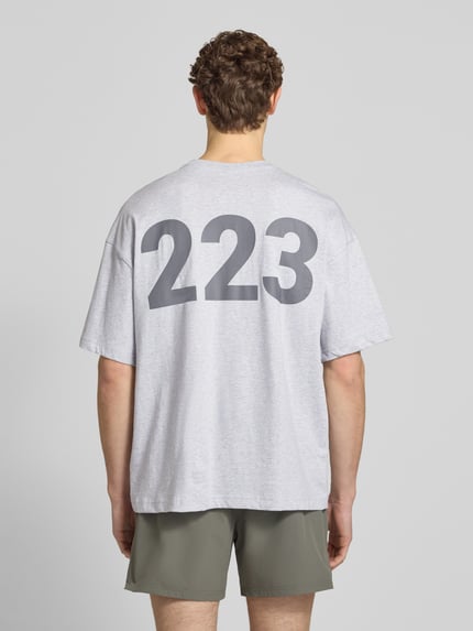 Männermodel trägt T-Shirt mit Label-Print und Rundhalsausschnitt von HALO, reine Baumwolle, boxy fit, Rückansicht, Ganzkörperansicht.