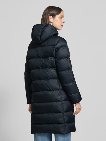 Frauenmodel trägt Steppmantel mit Daunen-Federn-Füllung Modell 'FROST' von Peak Performance in Dunkelblau, glatte Textur, Ganzkörperansicht Rückansicht. Regular Fit, Kapuze, Label-Stitching, Reißverschluss, Eingrifftaschen, Rückenlänge 99 cm, Schulterbreite 42 cm, Brustweite 53 cm, Ärmellänge 63 cm.