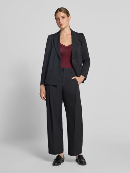 Frauenmodel trägt Slim Fit Tanktop aus Viskose-Mix Modell 'ROSA' von VERO MODA in Bordeaux und schwarzen Anzug, Ganzkörperansicht von vorne.