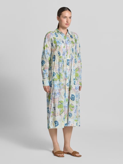 Frauenmodel trägt Relaxed Fit Midikleid aus reiner Baumwolle von Christian Berg Woman mit floralem Allover-Print, langärmelig, Knopfleiste, Falten, zarte Pastellfarben und weiche Textur, Ganzkörperansicht von vorne.