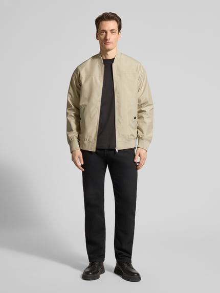 Männermodel trägt Jacke mit Stehkragen Modell 'clay' von Matinique, Regular-Fit, beige, Reißverschluss, Eingrifftaschen mit Druckknopfverschluss, Ganzkörperansicht von vorne. Rückenlänge 67 cm, Schulterbreite 45 cm, Brustweite 56 cm, Ärmellänge 66 cm bei Größe M.