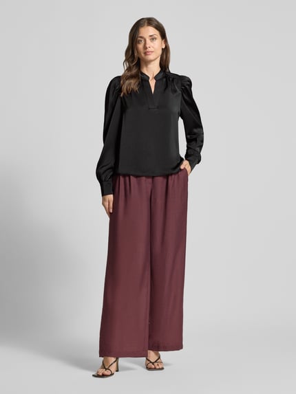 Vrouwenmodel draagt Langarmbluse met Stretch-Anteil Modell 'Rosslyn' van Neo Noir, zwart satijn, losse fit, v-hals, schouderplooien, ballonmouwen, volledige lichaamsvoorkant.