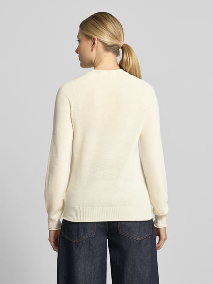 Frauenmodel trägt Regular Fit Pullover aus reiner Wolle von Lacoste in Creme, glatte Textur, dunkle Jeans, Ganzkörperansicht Rückansicht. Damen Pullover von Lacoste.