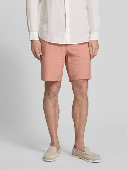 Männermodel trägt Regular Fit Bermudas aus Baumwoll-Mix Modell 'KARL' von SELECTED HOMME in Rosa mit Allover-Muster, Nahaufnahme Oberschenkel.