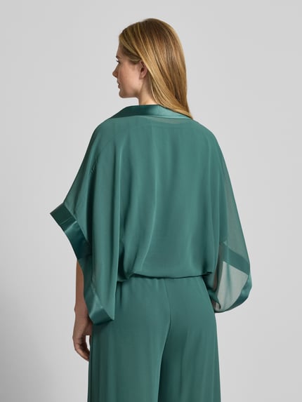 Vrouwenmodel draagt Bolero met wijde mouw van Vera Mont, los model, semi-transparant, 1/2-mouwen, ruglengte maat S 32 cm, achteraanzicht.
