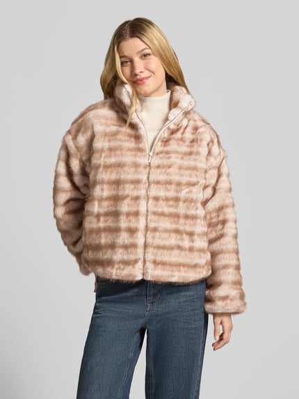 Kobiece modelka nosi Relaxed Fit Jacke aus Kunstfell mit Stehkragen od zero, beżowe sztuczne futro, zamek błyskawiczny, Ganzkörperansicht z przodu, długość tyłu w rozmiarze 36: 54 cm, szerokość ramion w rozmiarze 36: 47 cm, szerokość klatki piersiowej w rozmiarze 36: 56 cm, długość rękawów w rozmiarze 36: 56 cm.