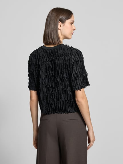 Frauenmodel trägt Regular Fit T-Shirt mit Rüschenbesatz und Rundhalsausschnitt von Jake*s Collection, schwarz, Material-Mix mit Stretch-Anteil, Rückenlänge 45 cm, Ganzkörperansicht Rückansicht.