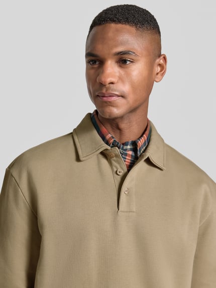 Männermodel trägt Poloshirt mit gerippten Abschlüssen von MCNEAL aus Baumwoll-Mix in Beige, lockerer Schnitt, Nahaufnahme Oberkörper.