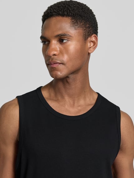 Mężczyzna nosi Slim Fit Tank Top aus Baumwoll-Mix von s.Oliver RED LABEL, czarny, krój slim fit, szerokie ramiączka, okrągły dekolt, bawełna, faktura drobnego ściągacza, widok na górną część ciała z przodu