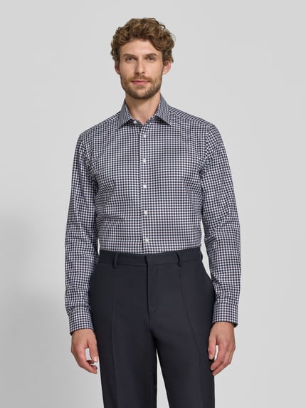 Männermodel trägt Regular Fit Businesshemd aus elastischem Baumwoll-Mix von Christian Berg Men im Karomuster, Ganzkörperansicht von vorne. Rückenlänge 78 cm, Schulterbreite 48 cm, Ärmellänge 66 cm, Kentkragen, Knopfleiste.