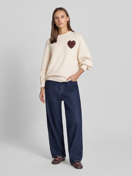 Frauenmodel trägt Regular Fit Pullover in Strick-Optik von REVIEW, cremefarben, langarm, gerippte Abschlüsse, Ganzkörperansicht von vorne.