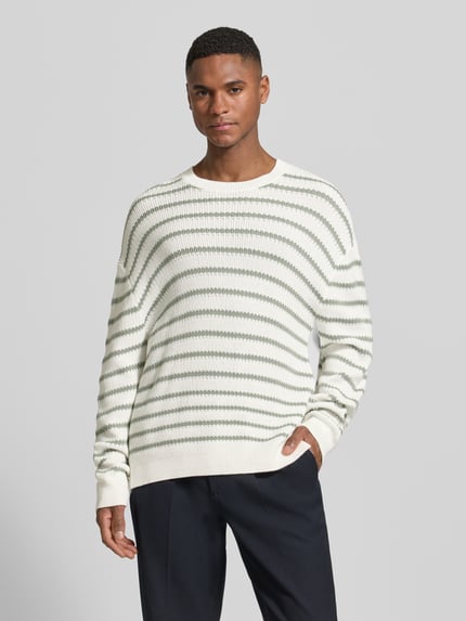 Männermodel trägt Strickpullover mit Rundhalsausschnitt von ARMANI EXCHANGE in Weiß mit grünen Streifen, Relaxed Fit, Nahaufnahme Oberkörper.