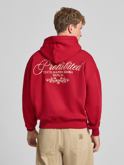 Männermodel trägt Relaxed Fit Hoodie aus Baumwoll-Mix mit Label-Stitching von PROHIBITED, rote Farbe, Ganzkörperansicht Rückansicht. Context: Herren Hoodie von PROHIBITED, Baumwoll-Mix, Relaxed Fit, Känguru-Tasche, Label-Stitching, elastische Abschlüsse, Rückenlänge bei Größe M: 67 cm, Ärmellänge bei Größe M: 60 cm.