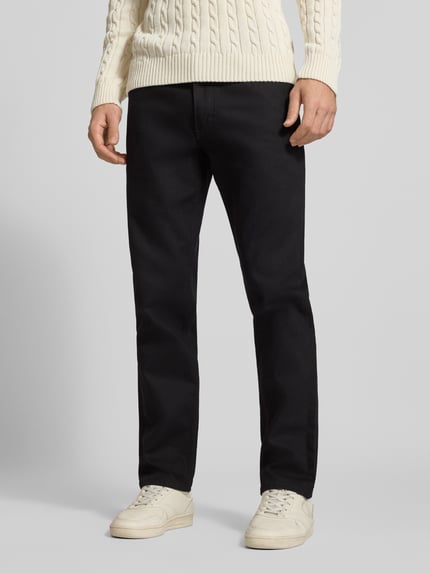 Männermodel trägt Tapered Fit Jeans mit Label-Patch Modell 'David' von LEE in dunkler Waschung, Denim, unifarben, Ganzkörperansicht von vorne.