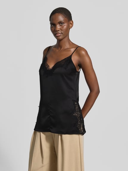 Frauenmodel trägt Spitzentop mit V-Ausschnitt Modell 'Brenda' von My Essential Wardrobe, schwarzer Satin, Regular Fit, Spitzendetails, verstellbare Spaghettiträger, Ganzkörperansicht von vorne.
