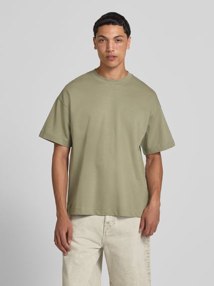 Männermodel trägt Herren T-Shirt mit Rundhalsausschnitt Modell 'BARRON' von Jack & Jones aus Baumwoll-Mix mit Stretch-Anteil, Relaxed-Fit, dezentes Hellgrün, glatte Textur, Rückenlänge bei Größe M 73 cm, Ganzkörperansicht von vorne.