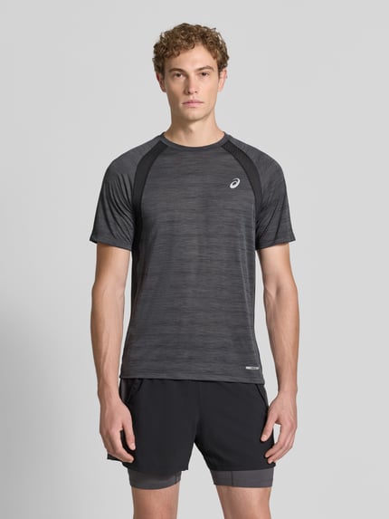 Männermodel trägt Regular Fit T-Shirt mit Logo-Print Modell 'Road' von ASICS TIGER in Schwarz mit semitransparenten Partien, Ganzkörperansicht von vorne.