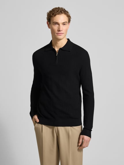 Męski model nosi Oversized Poloshirt aus reiner Baumwolle Modell 'CRAN' od SELECTED HOMME, czarny, długi rękaw, dzianina, widok z przodu.