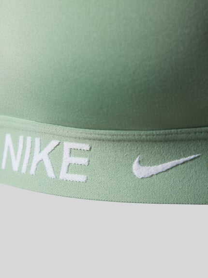 Frauenmodel trägt Slim Fit Sport-BH mit Logo-Print Modell 'Indy' von NIKE TRAINING aus Elastischer-Material-Mix, Nahaufnahme Oberkörper.