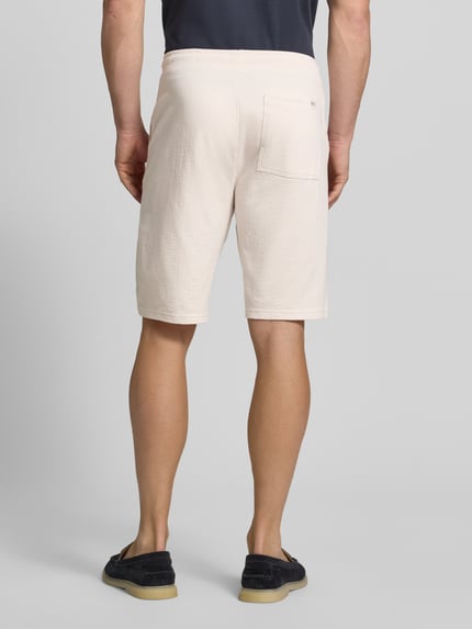 Männermodel trägt Relaxed Fit Sweatshorts aus reiner Baumwolle Modell 'DETROIT' von s.Oliver RED LABEL, Optik: Unifarben, fein strukturiert, Passform: Relaxed-Fit, Bundabschluss: Elastisch, Tunnelzug, seitliche Eingrifftaschen, Gesäßtasche, Material: Reine Baumwolle, Ganzkörperansicht Rückansicht.