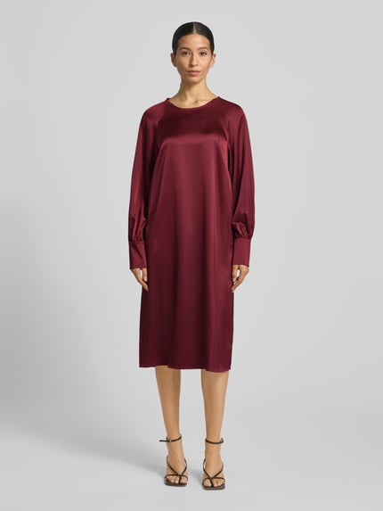 Modelka kobieca nosi bordową sukienkę do kolan Knielanges Cocktailkleid mit Rundhalsausschnitt Modell 'Aurea' od GUIDO MARIA KRETSCHMER WOMAN, prosty krój, długi rękaw, materiał z dodatkiem stretchu, pełny widok z przodu