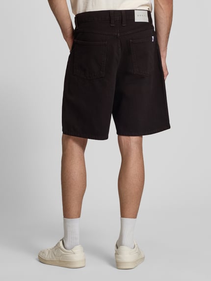 Männermodel trägt Straight Fit Shorts in Denim-Optik Modell 'Tyrell' von Edwin, reine Baumwolle, dunkler Ton, 5-Pocket-Design, Ganzkörperansicht Rückansicht.
