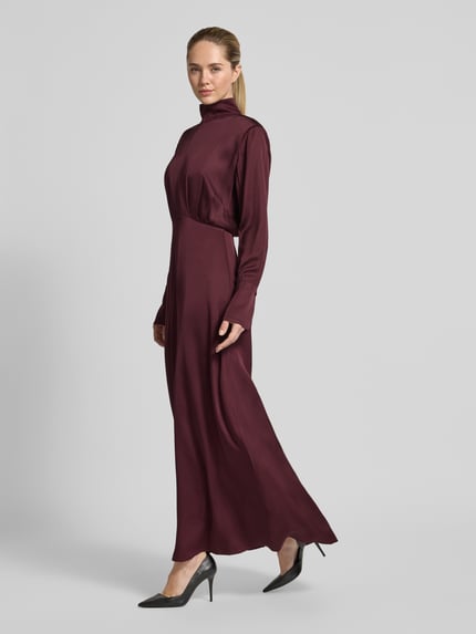 Frauenmodel trägt Fließendes Kleid in Maxilänge - curated by Isabelle Hartmann von Style Icon Collection, bordeauxfarben, Taillierte Passform, Stehkragen, Satin, Langärmeliges Design, Maxilänge, Rückenlänge bei Größe 36: 146 cm, Brustweite 35 cm, Ärmellänge 66 cm, Ganzkörperansicht von vorne.