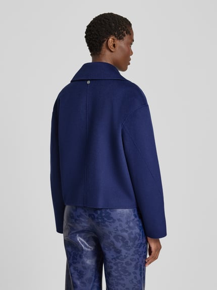 Frauenmodel trägt Relaxed Fit Jacke aus reiner Wolle von Marc Cain in Dunkelblau, strukturierte Optik, Reverskragen, Rückansicht, Ganzkörperansicht. Rückenlänge 54 cm, Schulterbreite 53 cm, Brustweite 56 cm, Ärmellänge 54 cm.