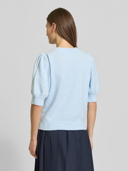 Modelka nosi Sweter z dzianiny Regular Fit Strickpullover mit Crew Neck Modell 'DOFFY' von Vero Moda, efekt: jednolity kolor, imitacja dzianiny, aplikacja z wyhaftowanym logo, dekolt okrągły, rękaw o dł. 1/2, zakończenie prążkowane, wykończenie materiału: dzianina. Widok całej sylwetki z tyłu.