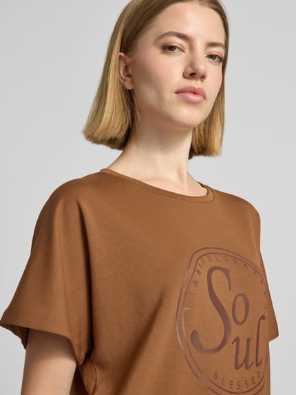 Frauenmodel trägt Damen T-Shirt mit Statement-Print Modell 'BANU' von Soyaconcept in Braun, Material-Mix mit Micromodal-Anteil, Relaxed-Fit, Rundhalsausschnitt, Nahaufnahme Oberkörper.